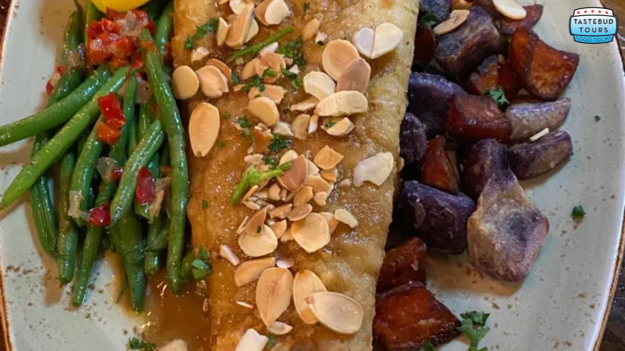 best-brunch-spots-in-new-orleans Plate with fish topped with almonds, green beans, and roasted potatoes.