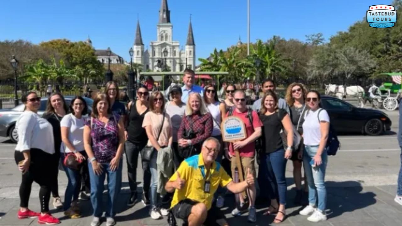 Group of people posing in front of a historic church with three spires on a sunny day.