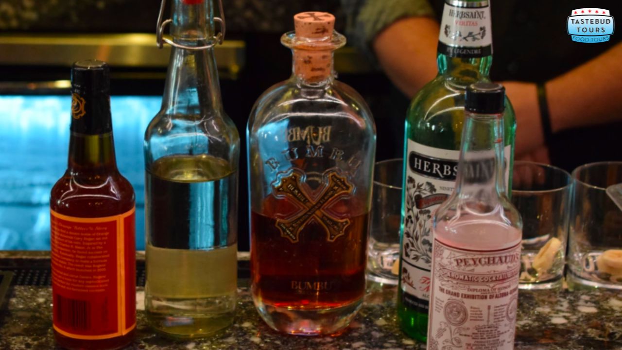 Five bottles of various spirits and liqueurs on a bar counter.