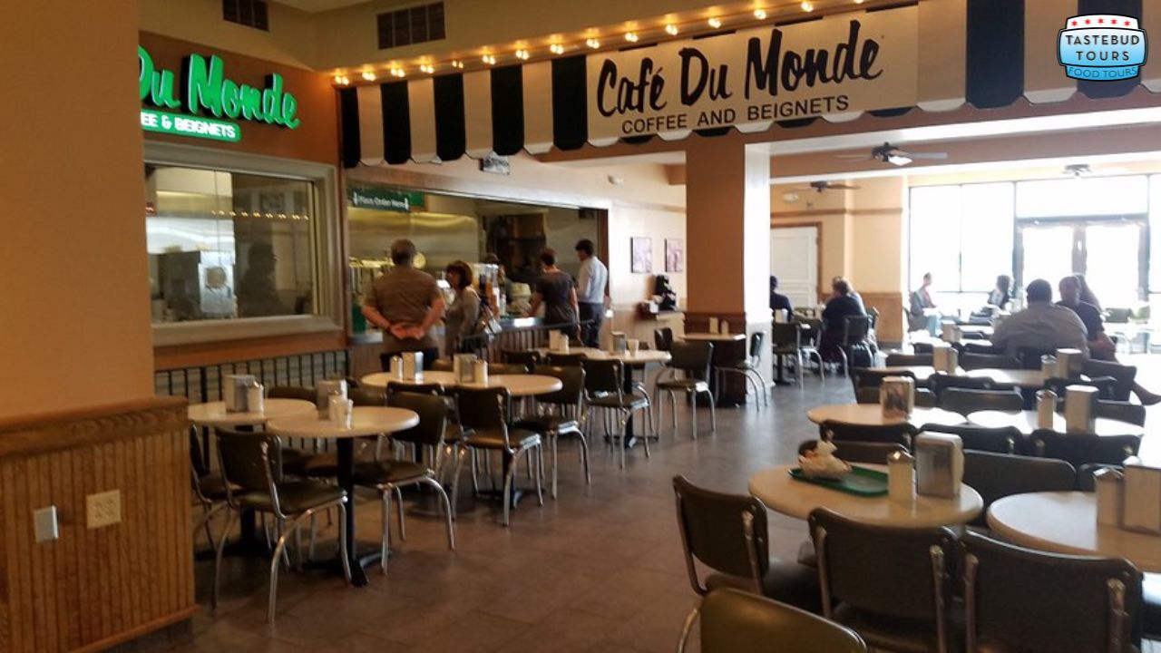 Cafe Du Monde interior with empty tables and a few people in line near the counter.