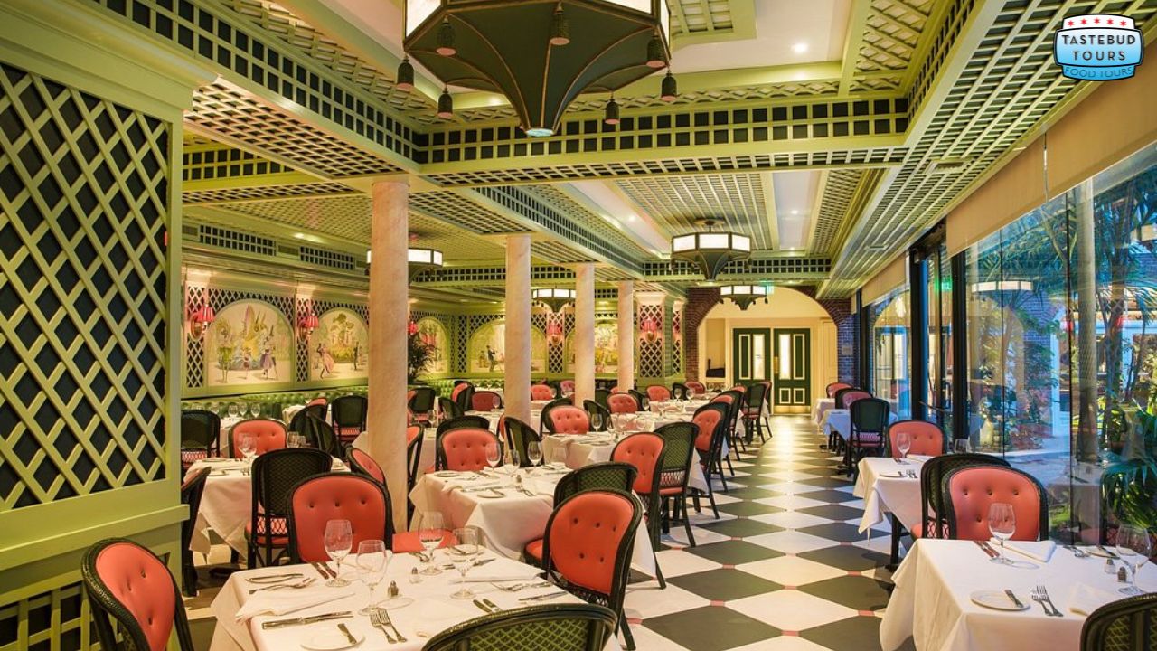 Elegant restaurant with green lattice decor, pink chairs, and checkered floor.