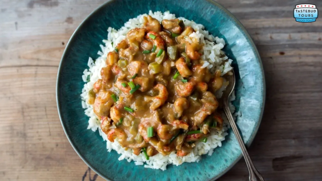 A plate of rice topped with a crawfish stew on a wooden table.