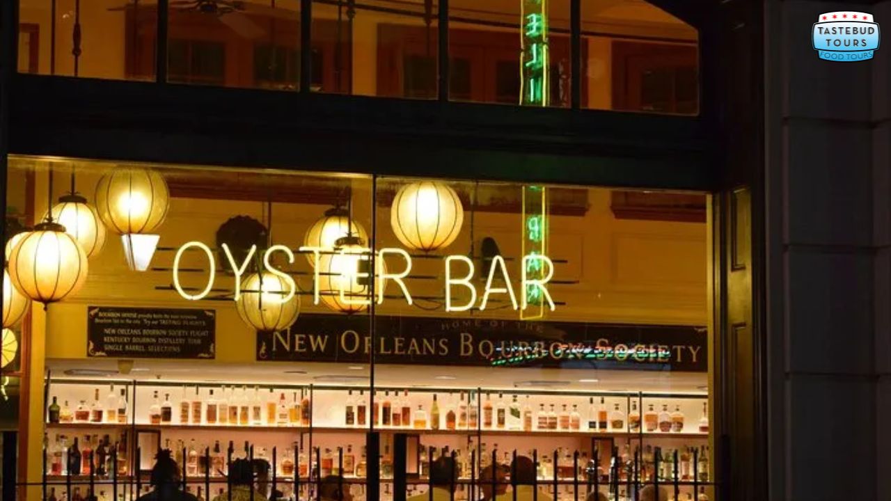 Neon sign for 'Oyster Bar' with glowing spherical lights and shelves of bottles visible through a window.