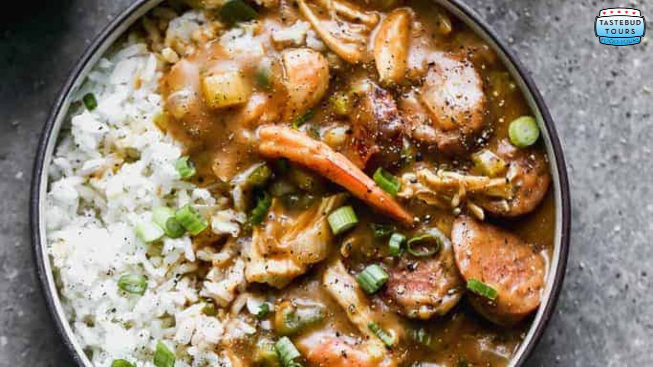 A bowl of gumbo with shrimp, sausage, and rice, garnished with green onions.