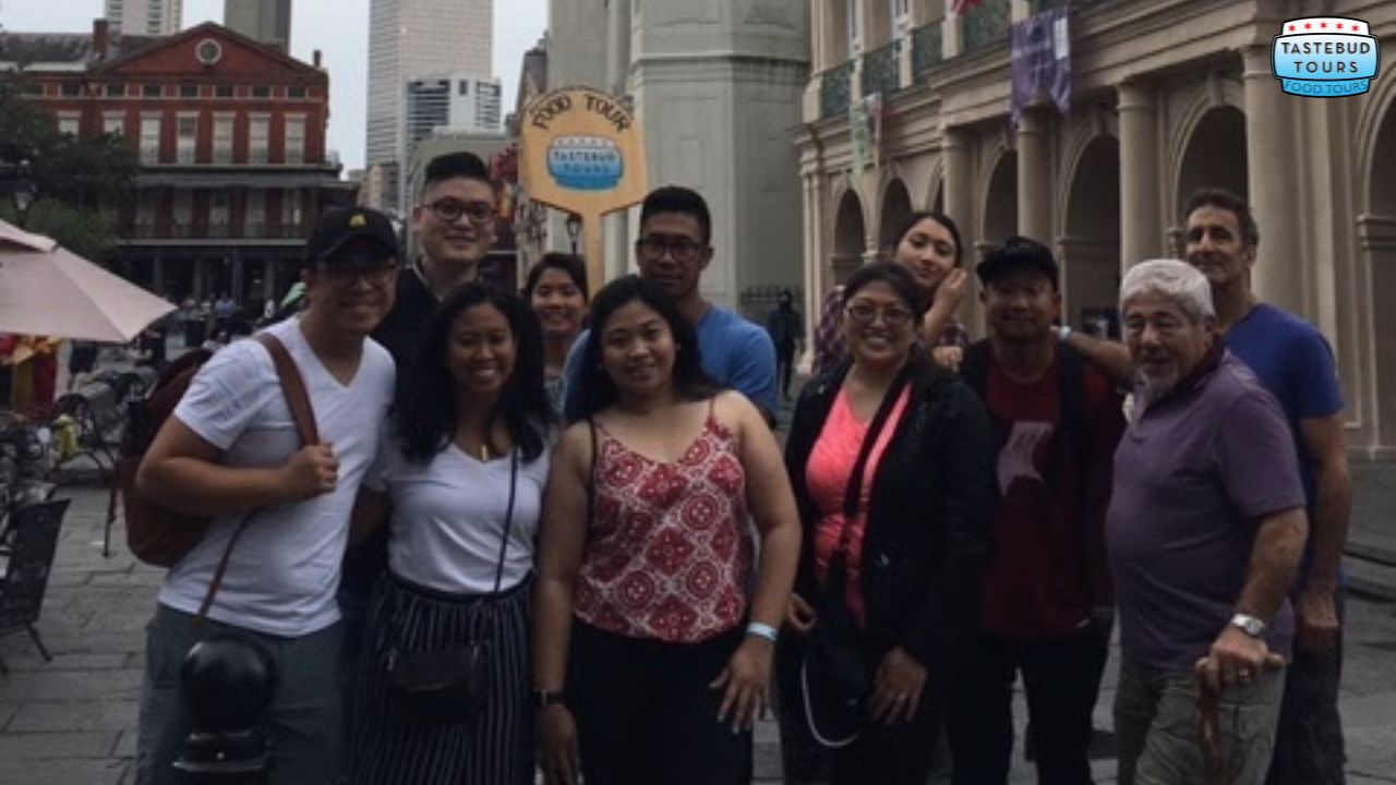 Group of people posing on a city street with a 'TasteBud Tours' sign in the background.
