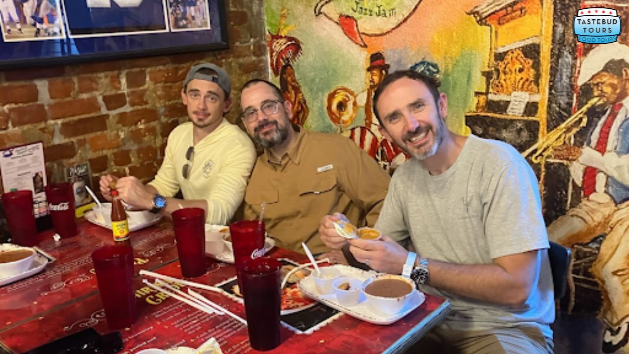 Three men seated at a table, enjoying a meal together with various dishes in front of them. 