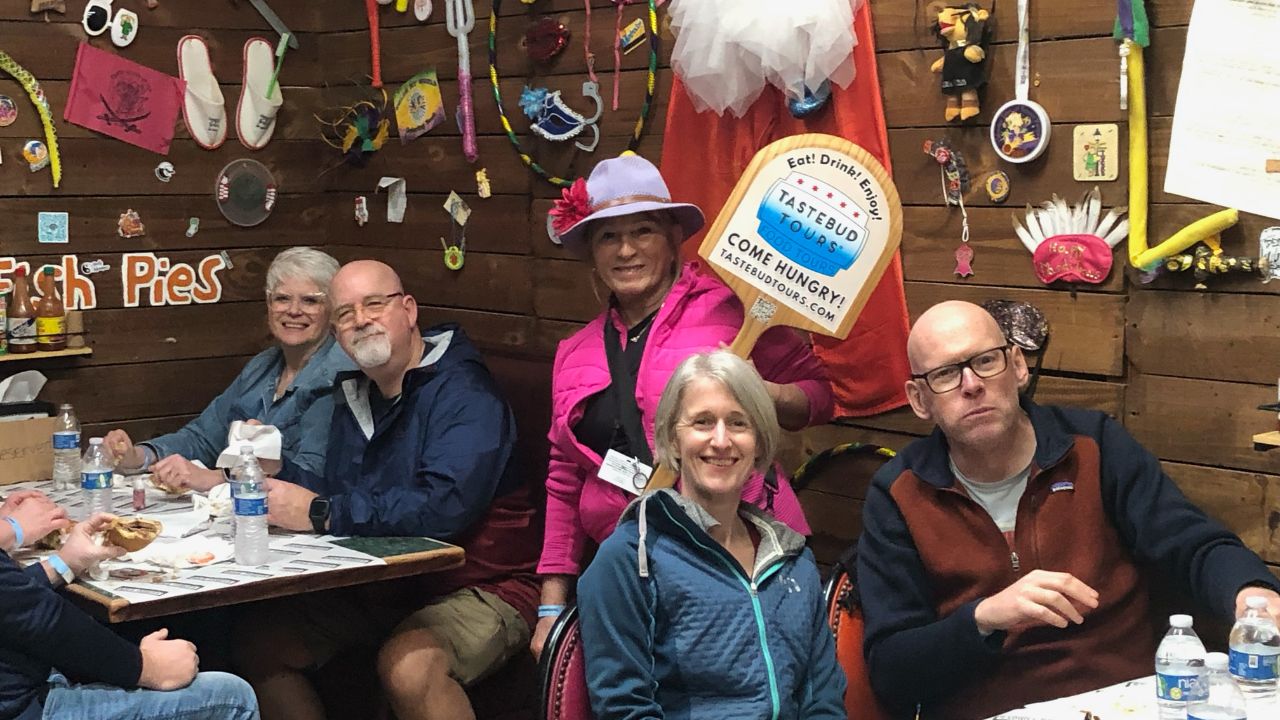 Group of five people at a restaurant table with eclectic wall decorations.