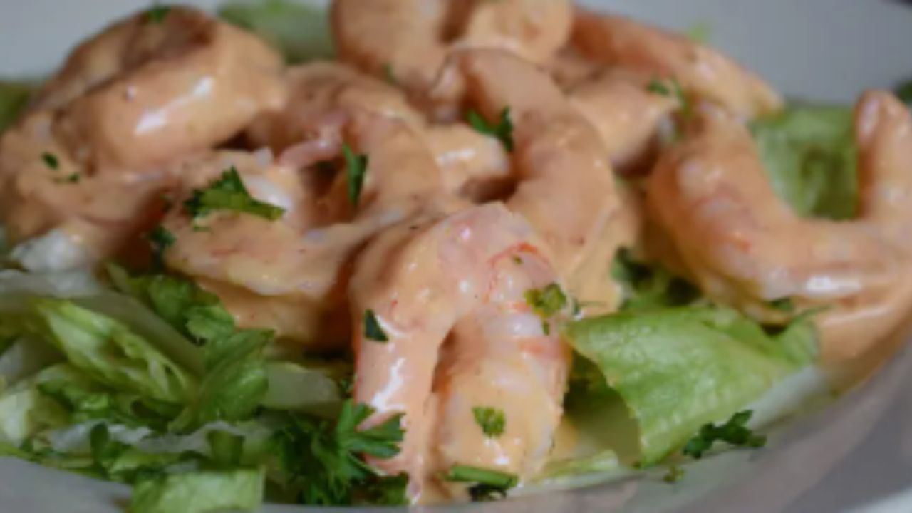 Shrimp in creamy sauce on lettuce with garnish.