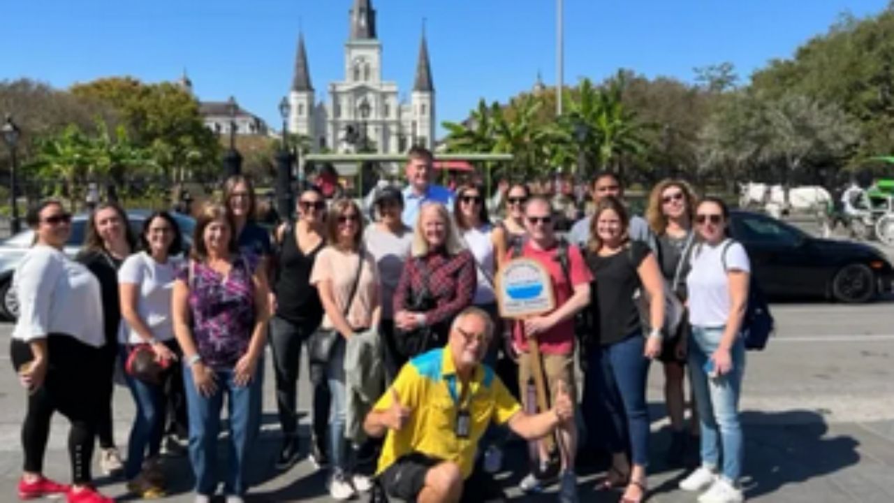 Group of people posing in front of a historic church with towers on a sunny day.