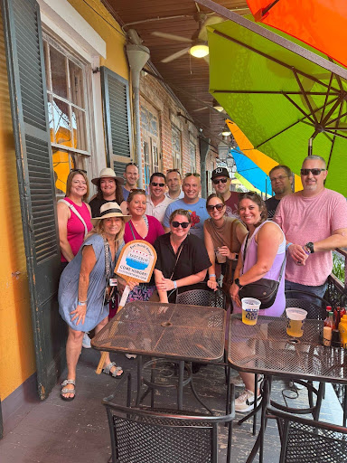 Group of people posing outside a cafe with colorful umbrellas.