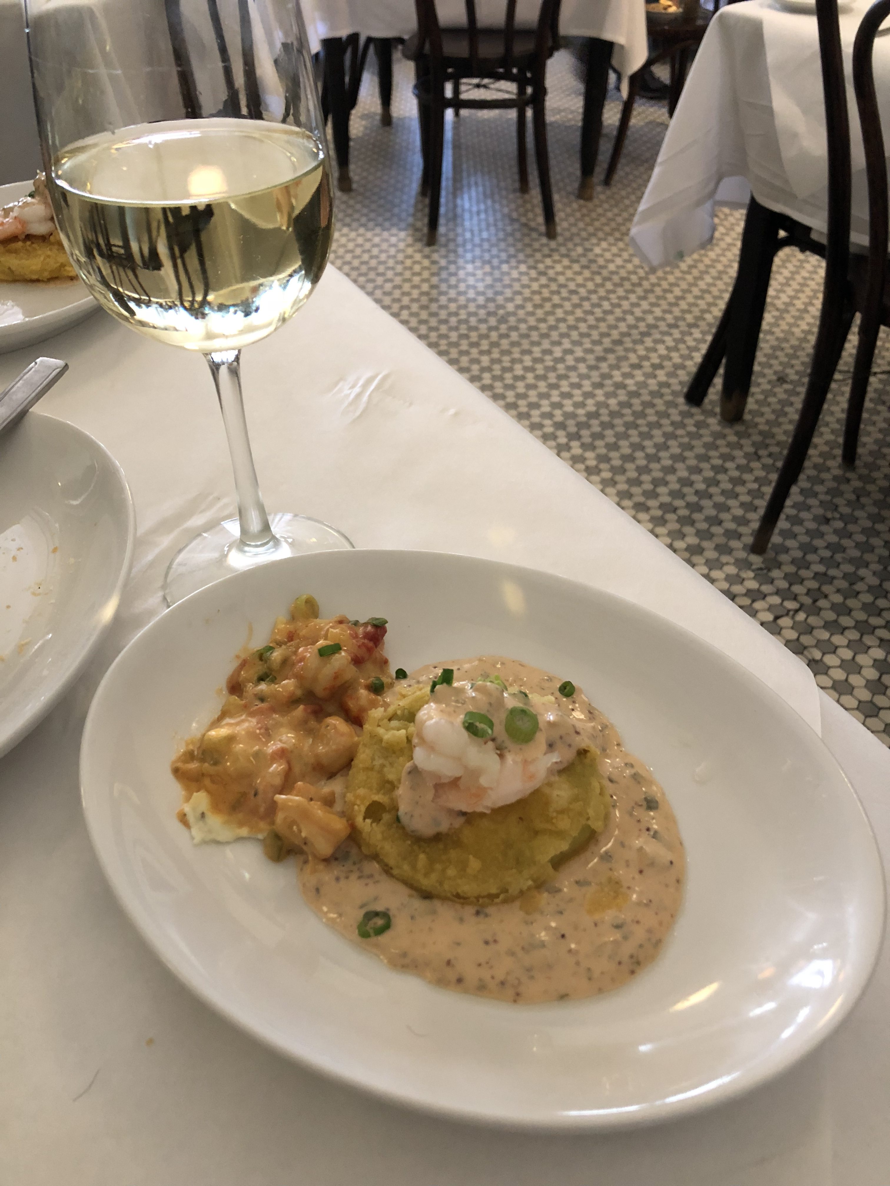 A creamy local dish served alongside a glass of wine in a New Orleans restaurant.