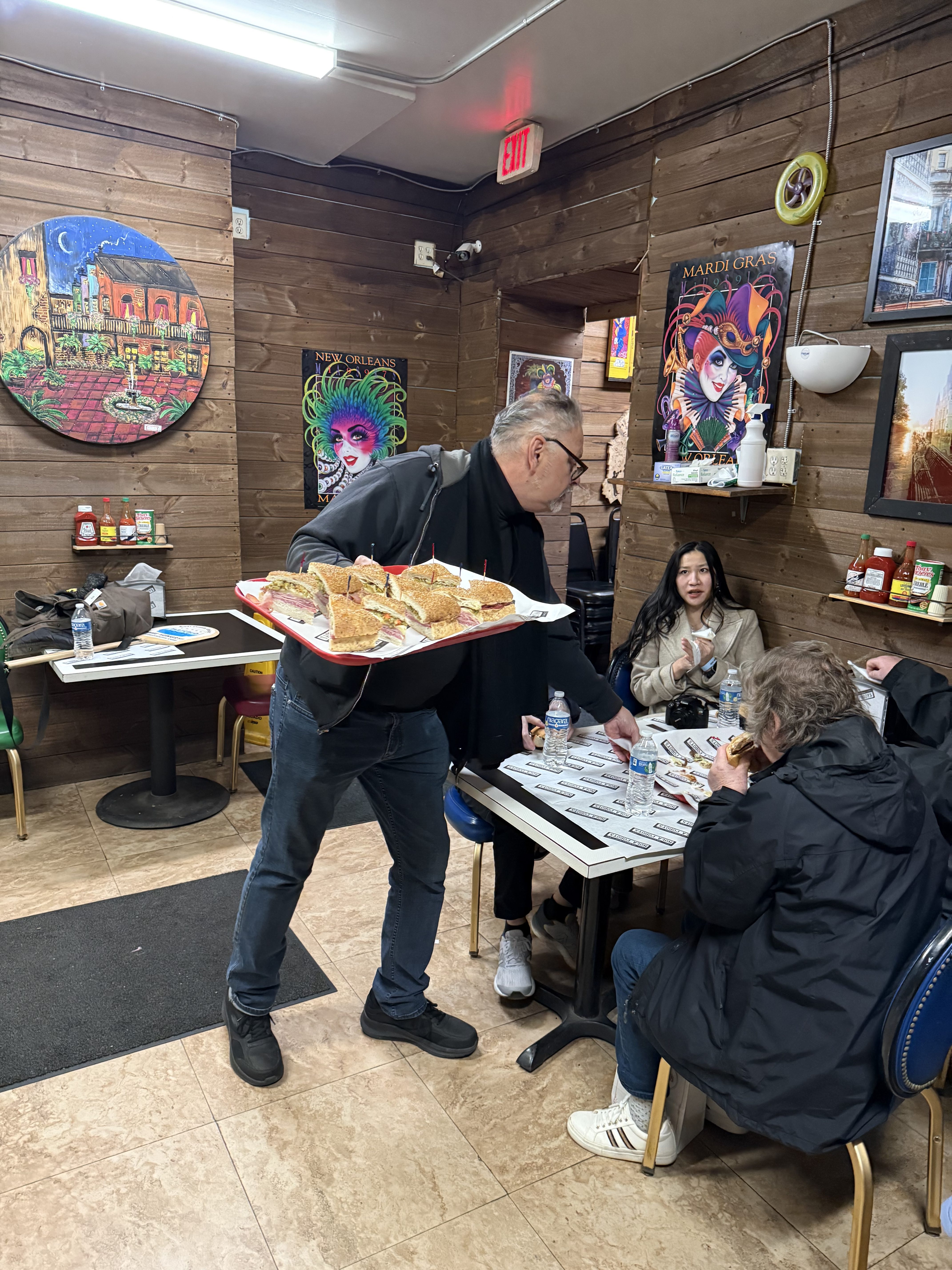 Family enjoying local sandwiches inside a casual restaurant during a guided food tour in New Orleans.