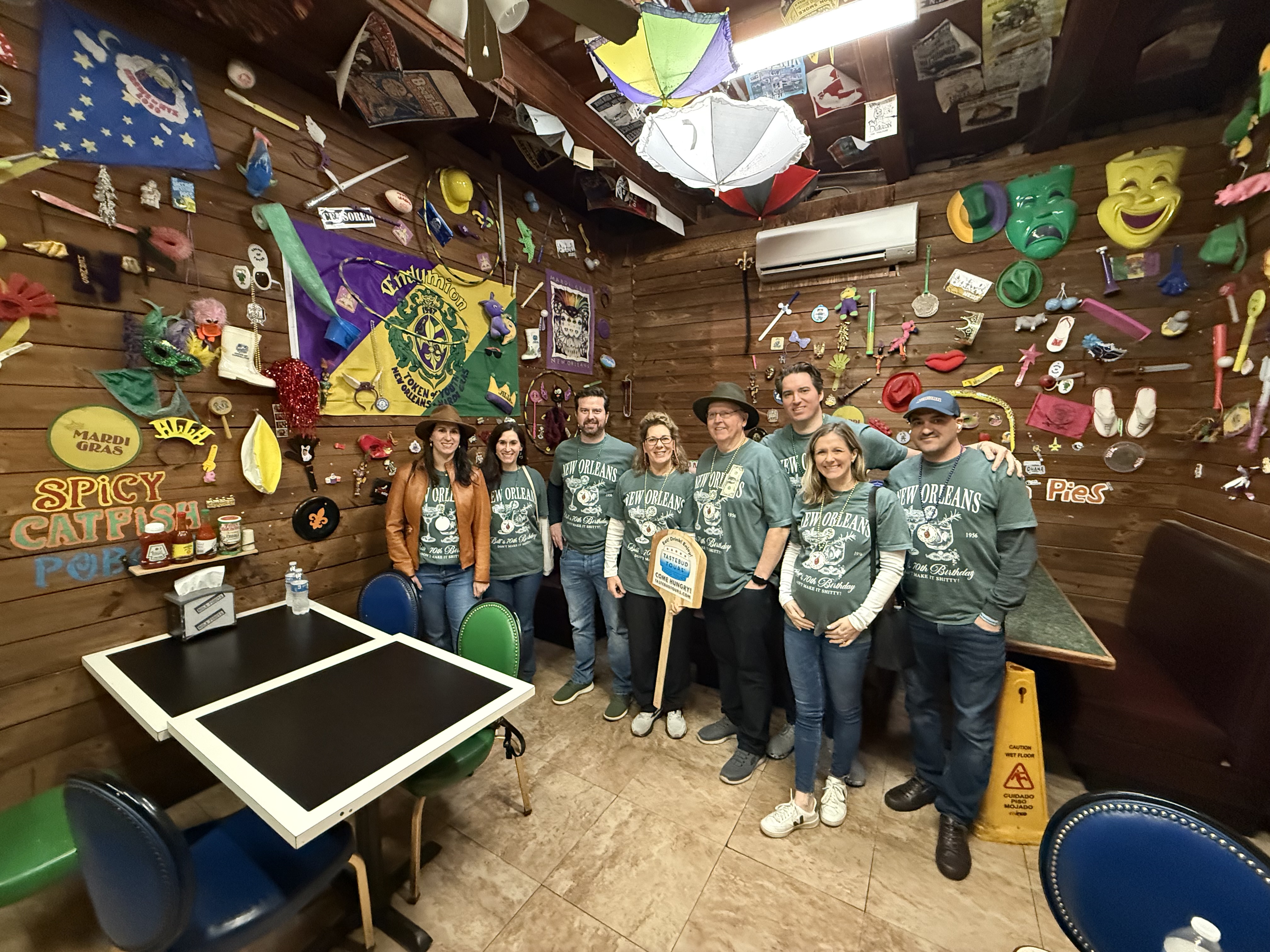 Group of visitors on a guided food tour in New Orleans inside a local restaurant with Mardi Gras decor and cultural elements.