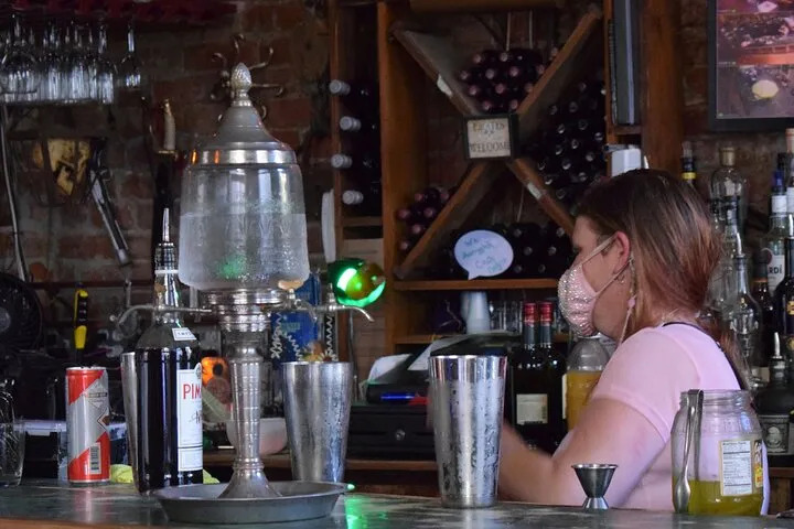 Bartender preparing craft cocktails behind a historic New Orleans bar.