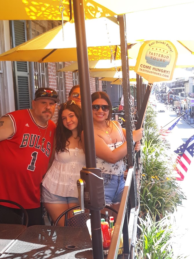 Guests posing on a shaded New Orleans balcony during a Tastebud Tours food tour.