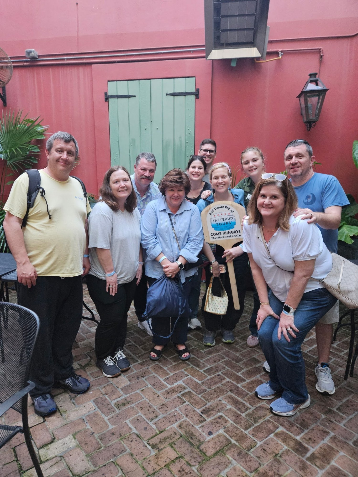 Tastebud Tours guests posing together in a colourful New Orleans courtyard during a guided food tour.