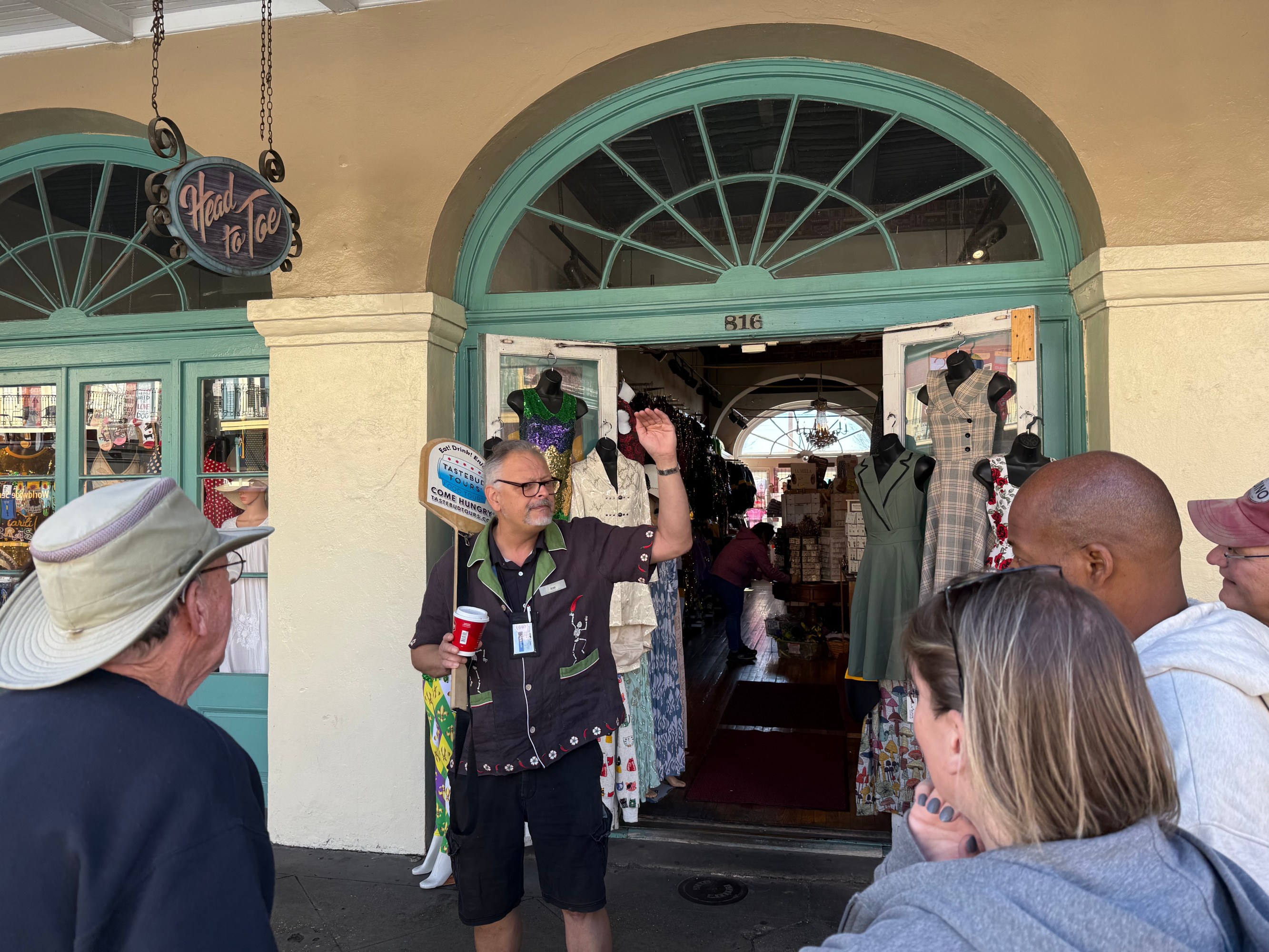 Food-tour guide speaking to guests outside a French Quarter shop.