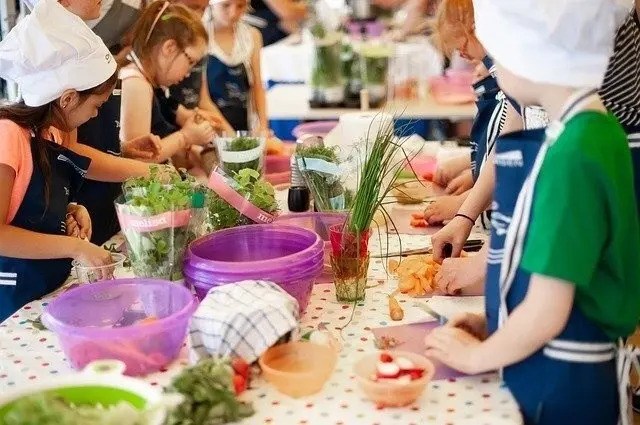 Mardi Gras cooking workshop with children preparing ingredients in chef hats.