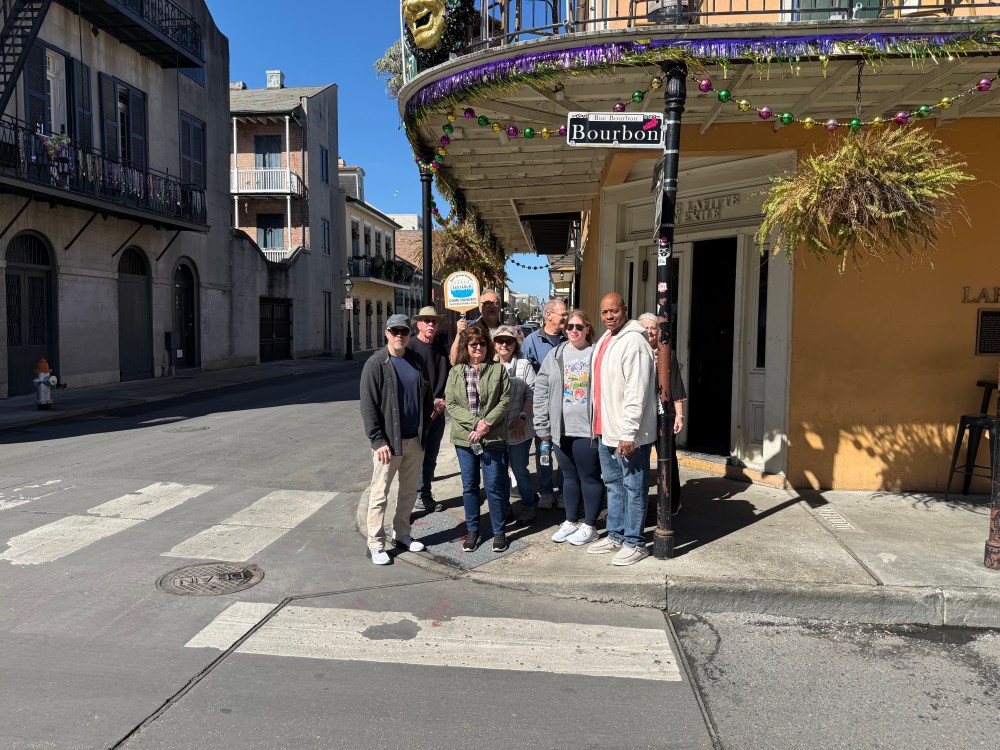 Mardi Gras food tour group posing on Bourbon Street in New Orleans’ French Quarter.