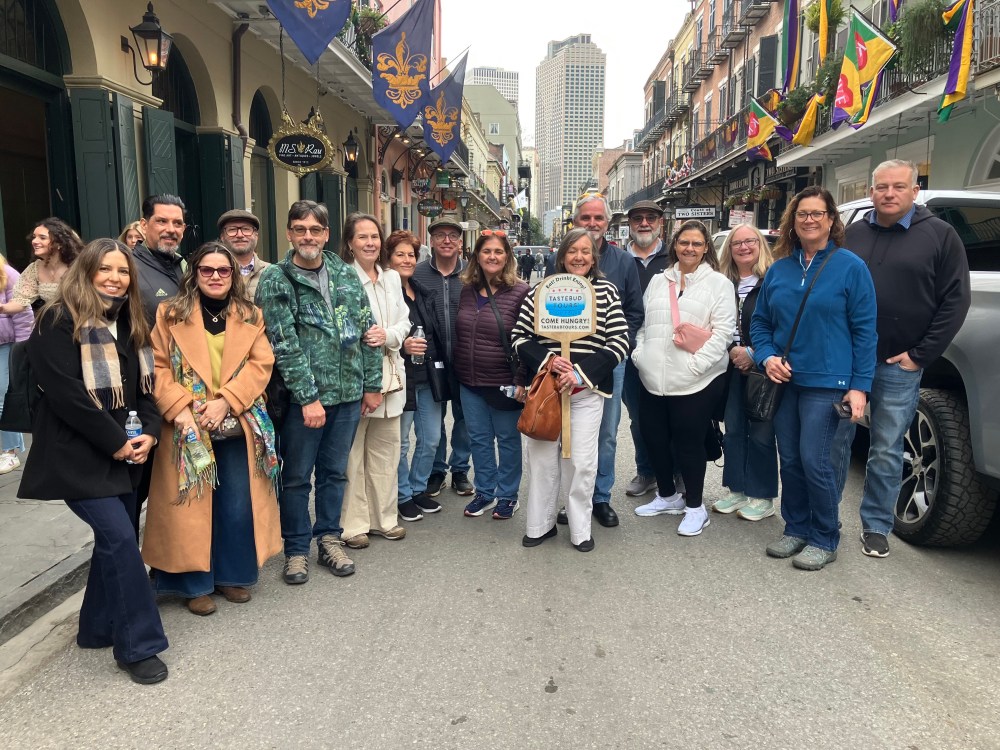 Tastebud Tours group posing on a decorated French Quarter street in New Orleans.
