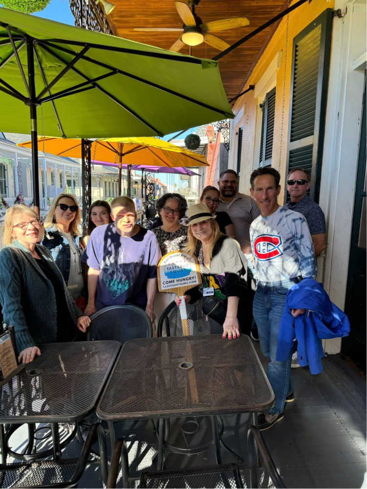 Tastebud Tours group posing on French Quarter balcony patio during a New Orleans food tour.