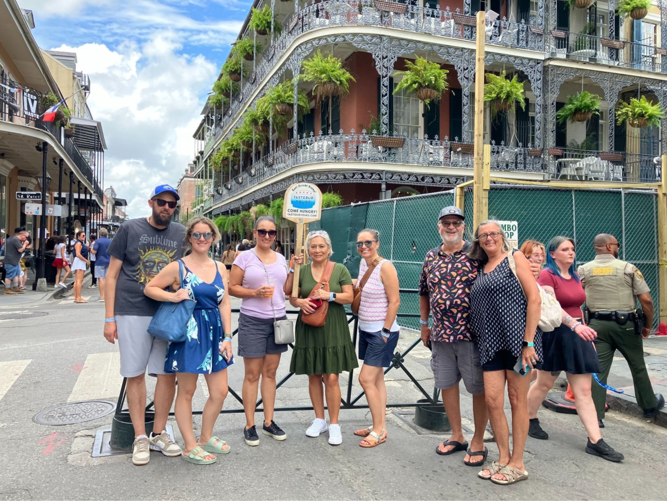 Tastebud Tours group posing on a French Quarter street beside ornate balconies in New Orleans.