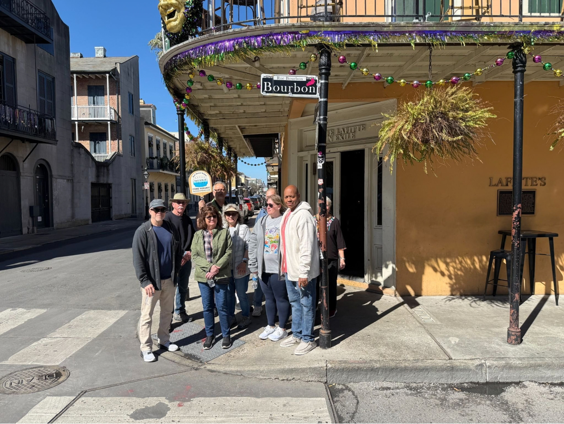 Tastebud Tours group standing on Bourbon Street in New Orleans French Quarter beneath festive decorations.