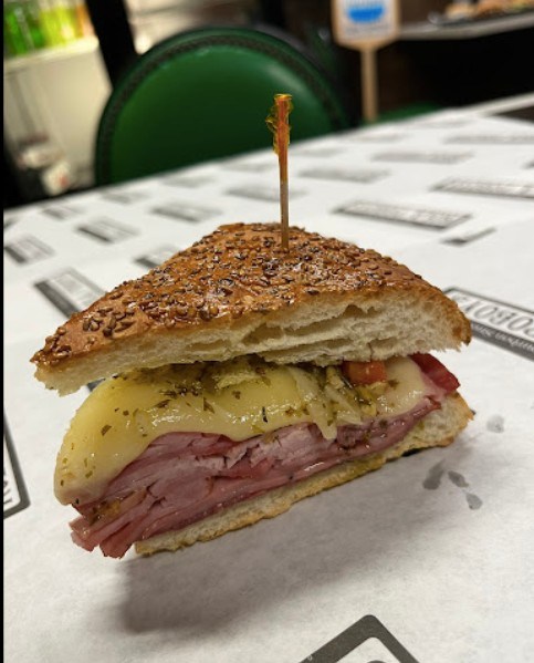 Close-up of a New Orleans muffuletta sandwich with layers of ham, cheese, and olive salad in toasted sesame bread.
