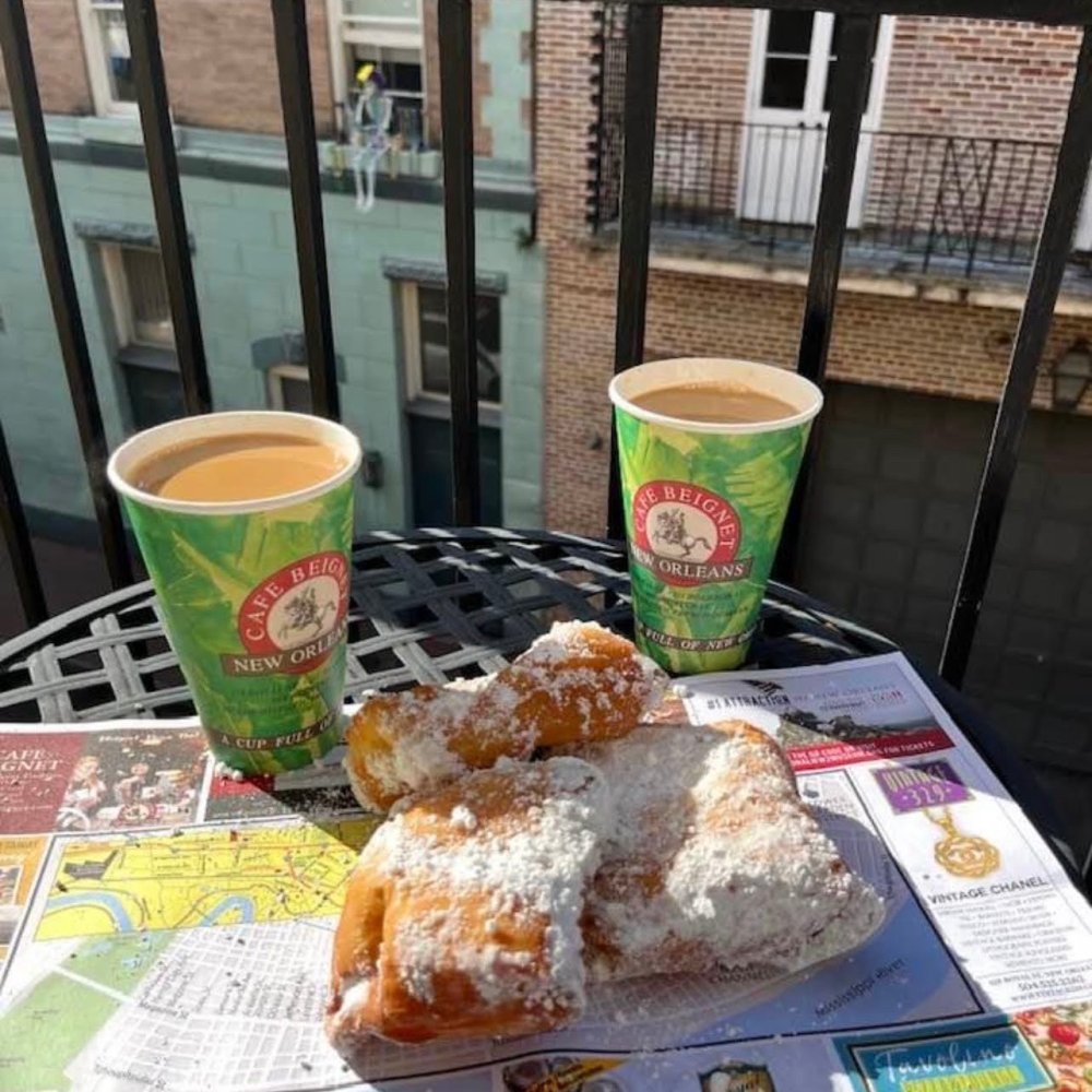 Fresh beignets covered in powdered sugar with two cups of coffee from Café Beignet in New Orleans.