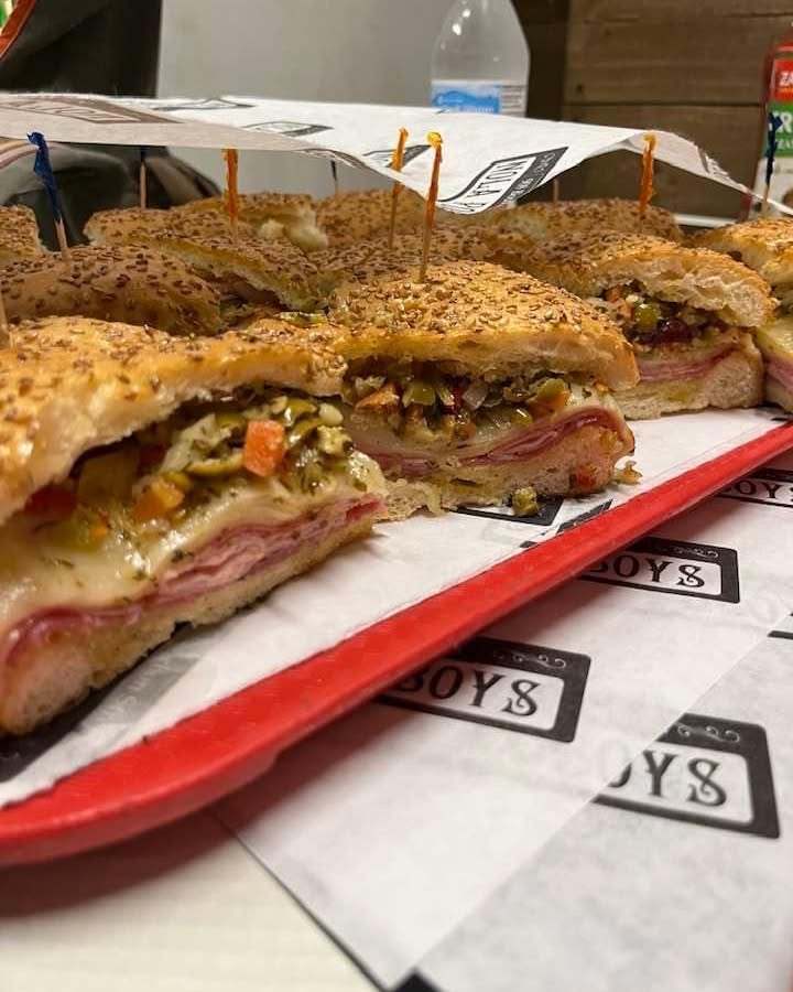 New Orleans muffuletta sandwiches filled with deli meats, cheese, and olive salad on sesame-seed bread.