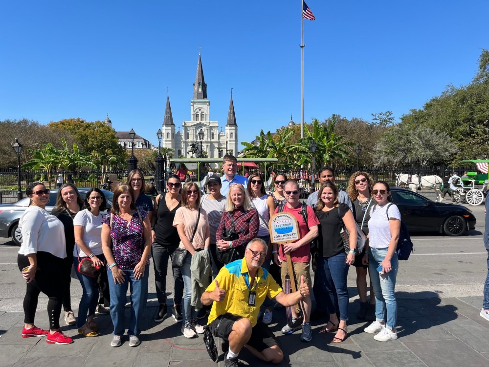 Tastebud Tours group posing for a photo near Jackson Square in New Orleans, with St. Louis Cathedral in the background.