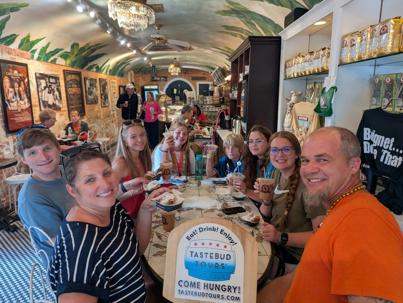 Tastebud Tours guests enjoying coffee, beignets, and local food together at a café in New Orleans.