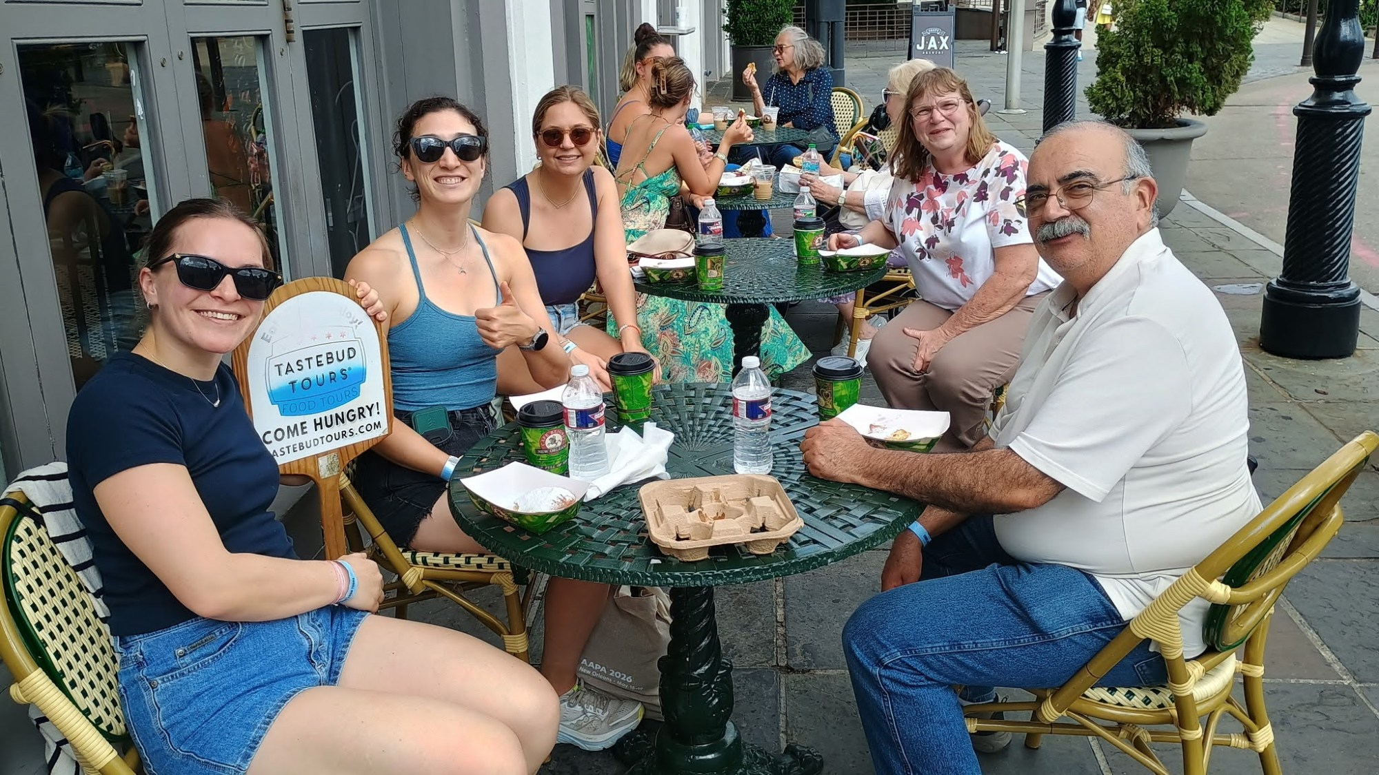 Tastebud Tours guests enjoying food and drinks together at an outdoor table during a New Orleans walking food tour.