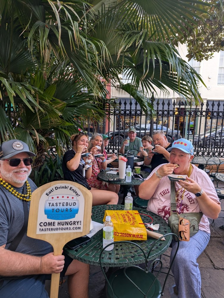 Tastebud Tours guests enjoying local food together at an outdoor French Quarter stop during a New Orleans walking food tour.