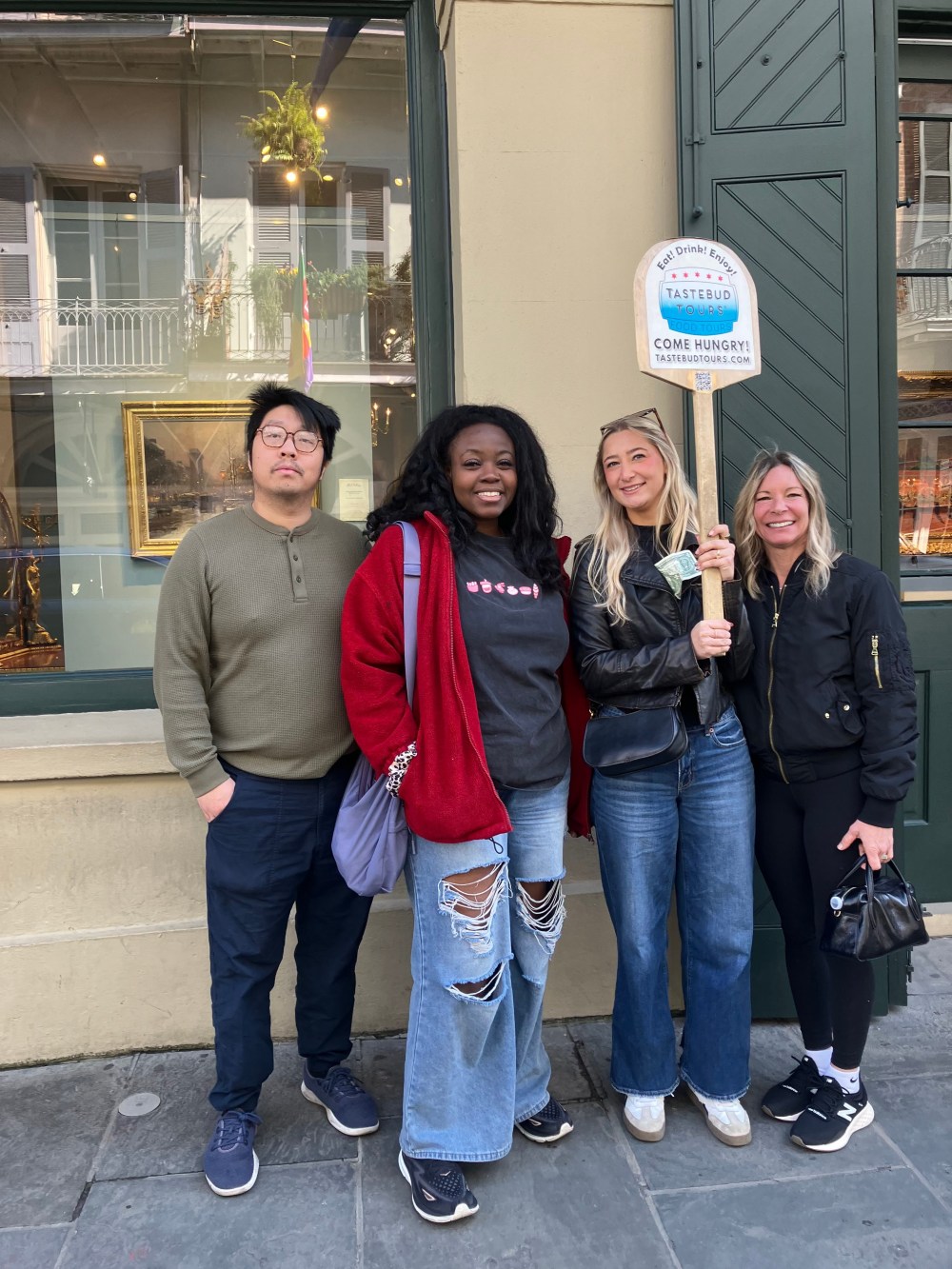 Tastebud Tours guests posing with their tour guide on a French Quarter street during a New Orleans food tour.