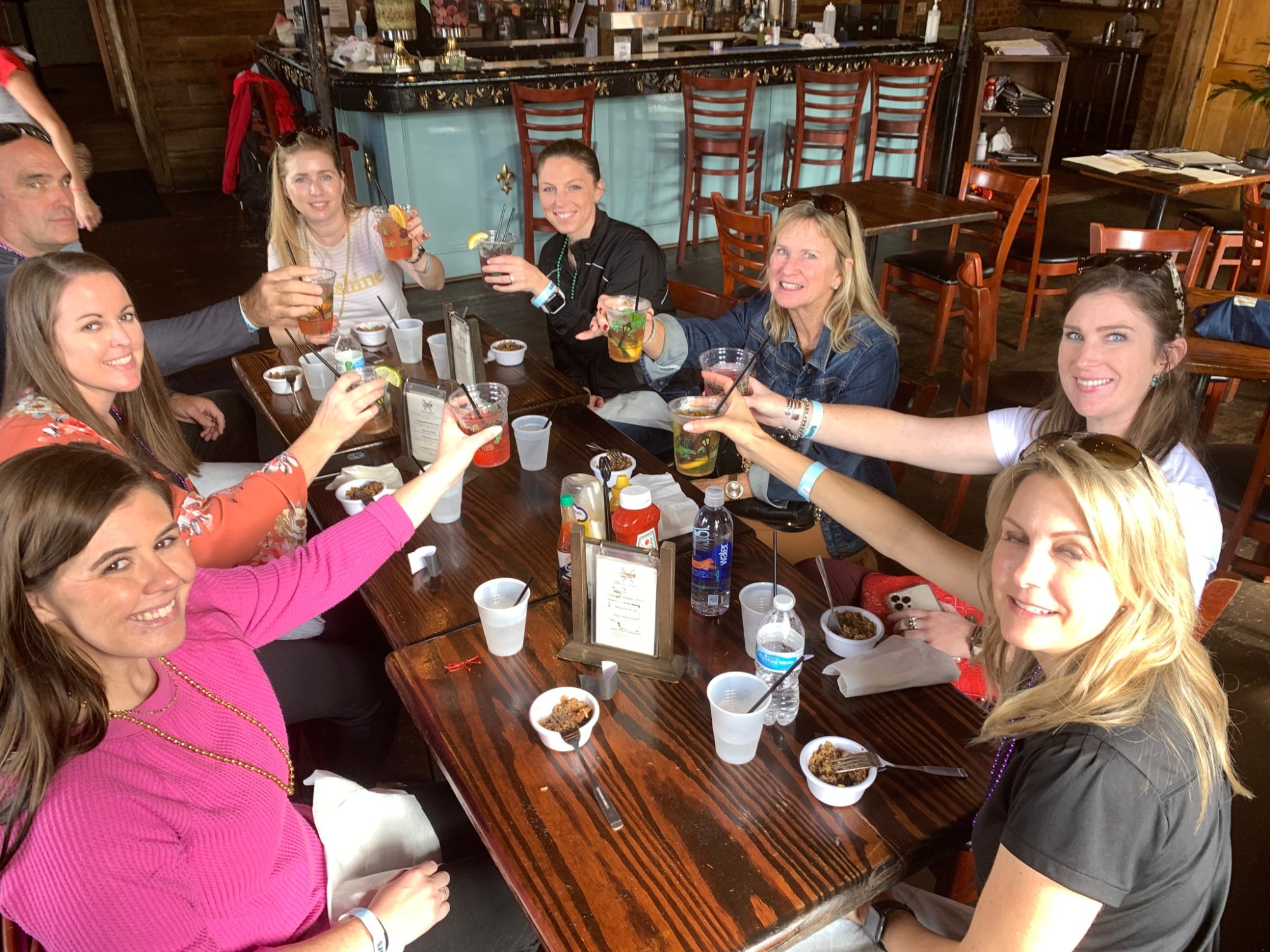 Tastebud Tours guests raising cocktail glasses around a restaurant table during a New Orleans food and drink experience.