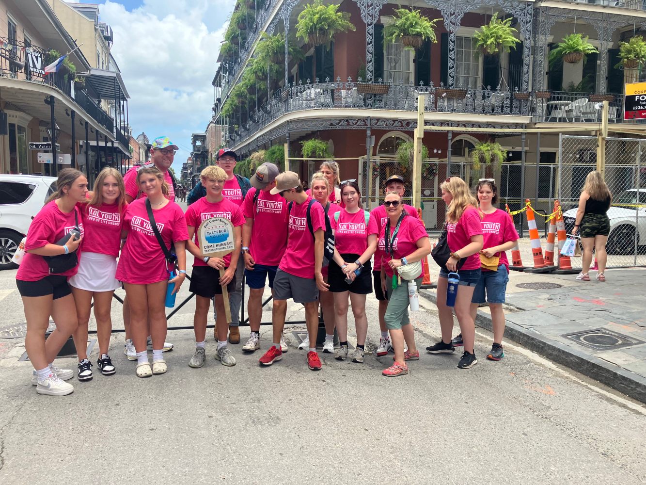 Tastebud Tours group posing on Royal Street with historic buildings and iron balconies in the background.